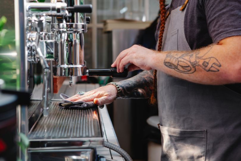 Barista cleaning coffee machine